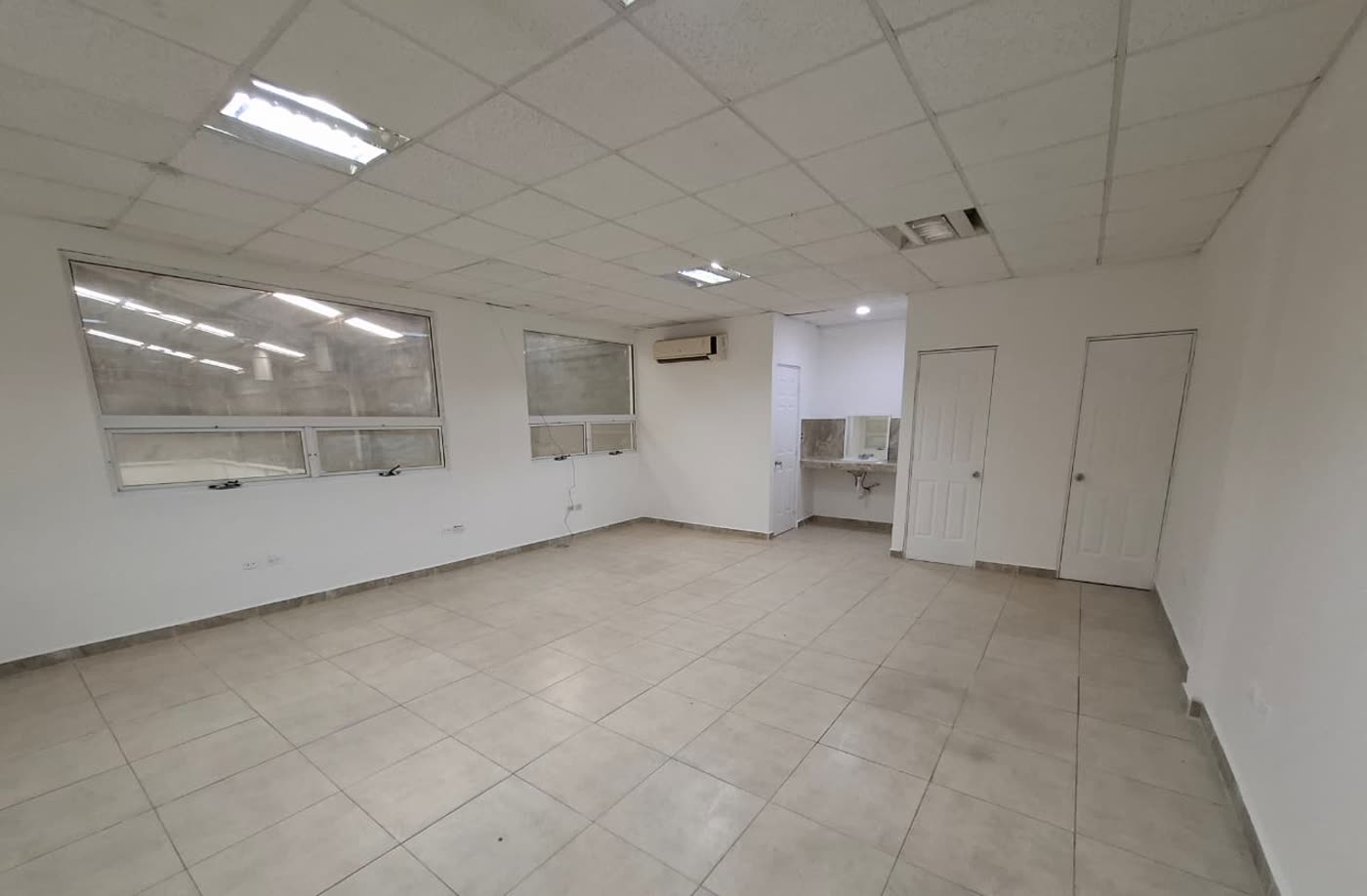 Oficina amplia con ventanas altas y equipo de aire acondicionado.