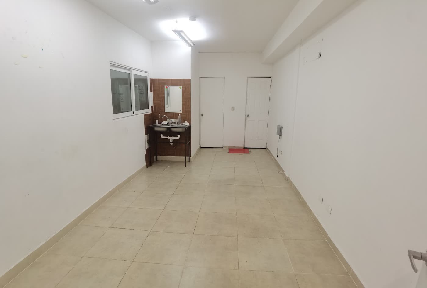 Corredor de servicios con lavabo y acceso a los baños.