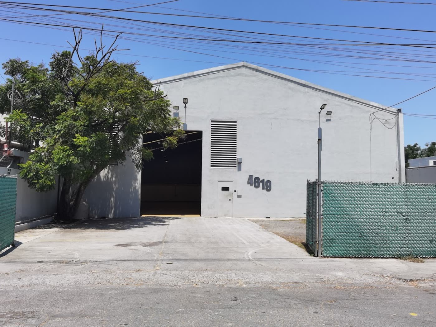 Fachada de la bodega desde la calle Encino, con el portón vehicular abierto.