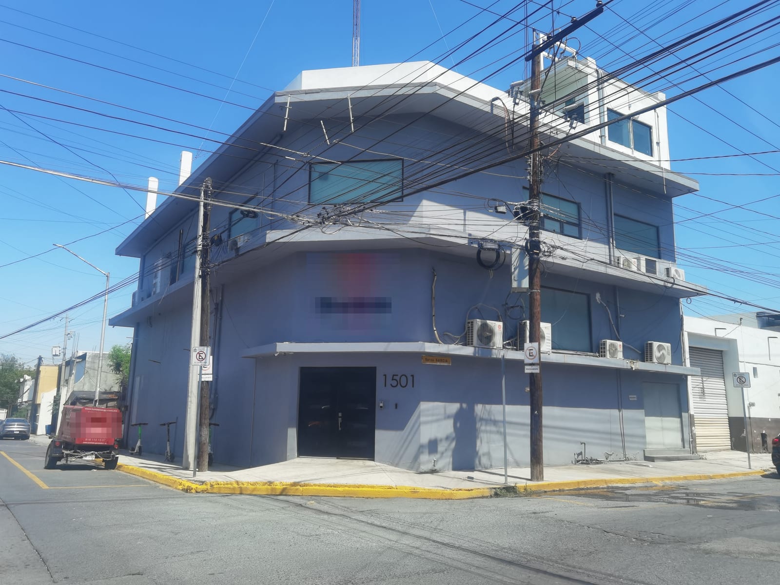El edificio en septiembre de 2026, desde la esquina de Garza García y Chiapas: tres niveles remodelados en gris azulado, con cantos de losa blancos, ventanas de cristal oscuro y el cuarto de azotea.