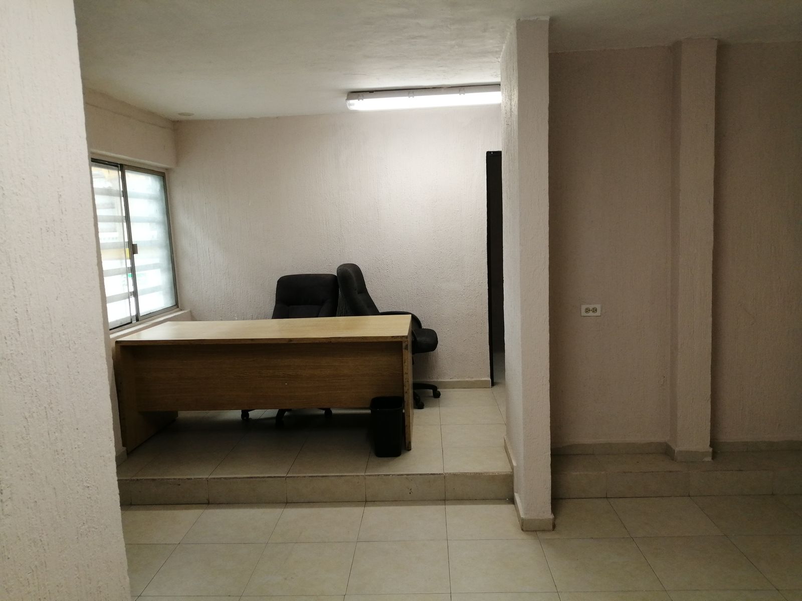 Oficina con ventana, escritorio y piso de cerámica.